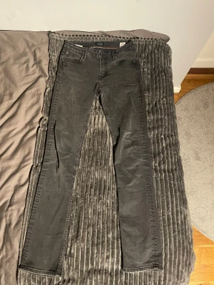 Svarta Crocker jeans  - Svarta jeans från Crocker med hög midja och raka ben. Klassisk femficksmodell med snygga bakfickor och orange söm på insidan. Jeansen är tillverkade i ett slitstarkt denimtyg och har en stilren look som passar till sneakers eller boots.