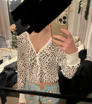 Leopardmönstrad croppad tröja - Säljer en croppad sovtröja med leopardmönster i vitt och brunt. Tröjan har långa ärmar, breda vita muddar och v-ringning med knappar framtill. Perfekt för dig som vill sticka ut med ett djurmönster och gillar trendiga detaljer. Jätte skön men är från SHEIN.