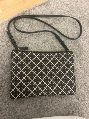 By Malene Birger kuvertväska - Snygg svart handväska från Malene Birger med beige rutigt mönster. Perfekt storlek för det viktigaste och har en stilren look med guldfärgade detaljer. Pris kan diskuteras lite vid snabbt köp