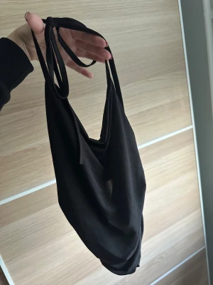 Festtopp  - Svart draperad festtopp med halterneck knytning. Aldrig använd. Öppen rygg och drapering i sidorna . Ingen storleksangivelse men motsvarar ca xs-s. 