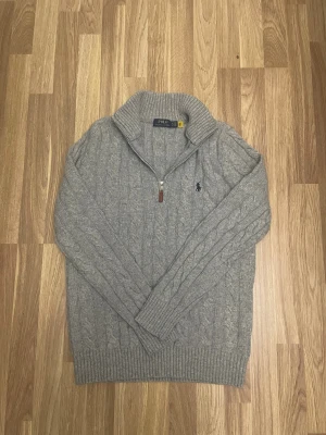 Grå stickad polotröja Polo Ralph Lauren - Säljer nu en grå kabelstickad half zip från polo Ralph lauren i storlek M. Mycket bra skick 10/10 som ny, mycket bekväm, klassisk och stilig. 100% äkta, mått📏: Längd 64 cm, Armhåla till Armhåla 49cm, midja 46cm. Skriv vid frågor eller funderingar 🙌🏼