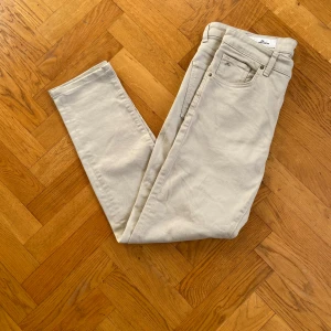 Beige chinos från J.Lindeberg 32/34 - Snygga beige chinos från J.Lindeberg i storlek 32/34. Byxorna har klassisk femficksdesign, raka ben och diskret svart läderpatch med logga bak. Tillverkade i mjuk bomull med lite stretch för extra komfort.