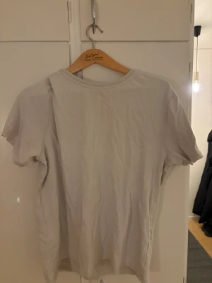 Ljusbeige basic t-shirt i bomull - En enkel och stilren ljusbeige t-shirt med rund hals och korta ärmar. T-shirten är tillverkad i mjuk bomull och har en normal passform som sitter skönt på kroppen. Perfekt för dig som gillar minimalistisk och clean stil.
