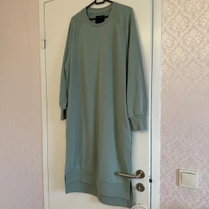 Grön sweatshirtklänning med långa ärmar - Enkel och stilren ljusgrön sweatshirtklänning med rund halsringning och långa ärmar. Endast använd 1 gång. Köpt förra året. Klänningen har ribbade muddar vid ärmslut och nederkant samt en loose passform som ger en avslappnad look. 🥰