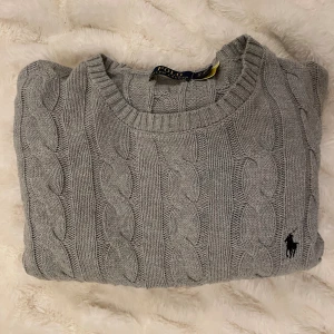 Grå kabelstickad tröja Polo Ralph Lauren - Snygg grå kabelstickad tröja från Polo Ralph Lauren med rund hals | Nypris runt 2500kr