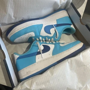 Nike Air Force 1 '07 LV8 blå/vit - Nike Air Force 1 '07 LV8 sneakers i fräscha blå och vita färger. Köptes för 2 år sedan för 1500ca men bara stått sen dess, använda några fåtal gånger, inga fel på dem endast lite creassade. Passar dig med 42/43