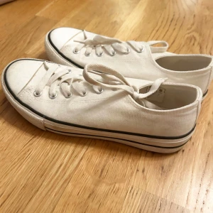 Vita låga sneakers  - Klassiska vita tyg sneakers med lågt skaft, rund tå och snörning. 