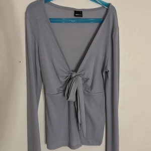 Ljusblå knyttopp från Gina Tricot - Supersnygg ljusblå knyttopp från Gina Tricot med lång ärm och knyt framtill. Toppens material är mjukt och stretchigt. Djup v-ringning och enkel design som passar till mycket.💗Pris kan diskuteras.