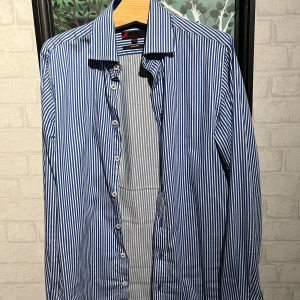 Randig skjorta  - Säljer en slim fit skjorta från Dressmann i storlek S med blå och vita ränder. Skjortan har klassisk krage, långa ärmar och knäppning framtill. Perfekt för dig som gillar stilren och fräsch look. 
