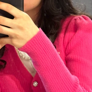 Rosa kofta från Zara med diamantknappar - Superfin rosa kofta från Zara med glittrande diamantknappar. Koftan är stickad, har lång ärm och en croppad passform. Perfekt för dig som vill ha en färgklick i garderoben och gillar snygga detaljer.