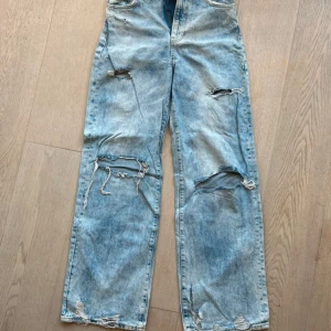 Ljusblå slitna jeans med raka ben - Ljusblå jeans med flera slitningar och hål på benen för en riktigt avslappnad och trendig look. Raka ben och klassisk femficksmodell. Perfekta för dig som gillar en edgy streetstyle.