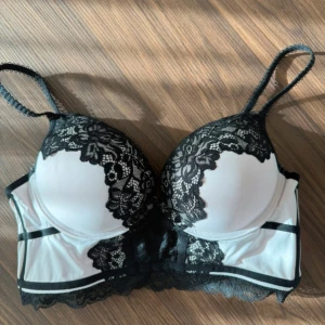 Vit och svart spets korsett - Säljer en snygg korsett i vit och svart med blommig spetsdetalj. Axelbandslös design med vadderade kupor och bred spetskant nedtill. Perfekt för att lyfta din outfit med en elegant touch. Materialet är polyester och spets. Endast provad! Säljes då den tyvärr var för stor för mig. 🌸💞