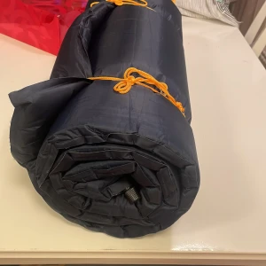 LIGGUNDERLAG SJÄLVUPPBLÅSBAR   -  Bekvämt självuppblåsande liggunderlag till camping  eller friluftsliv med polyuretanskum och polyesteröverlag B60 x L190 x H7,5 c. Ventil på både änden. Använts endast en gång. Ny pris 450kr.