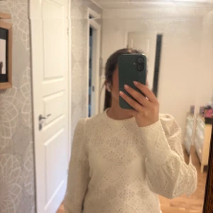 Vit spetsblus med puffärm - Säljer en vit blus med spets och snyggt hålmönster. Blusen har puffiga långärmar och rund halsringning.  Använd fåtal gånger då jag inte trivdes i modellen, så i nyskick. Normal i storleken. 