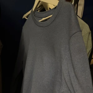 Grå stickad tröja med rund hals - En enkel och stilren grå stickad tröja med rundad halsringning och långa ärmar. Perfekt för dig som gillar en clean look och vill ha något mjukt och bekvämt att dra på sig när det är lite kyligt ute.