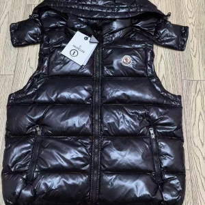 Svart dunväst från Moncler - Snygg svart dunväst från Moncler med glansig finish och klassisk logga på bröstet. Västen har två dragkedjefickor framtill, hög krage och quiltad design. Perfekt för lager-på-lager och streetstyle. Innerfoder med Moncler-etikett och serietidningsdetalj. Med nfc