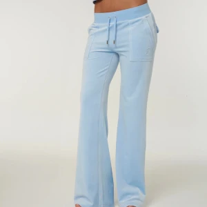 Juicy couture byxor  - Snygga ljusblå mjukisbyxor med bootcut-passform och bred resår i midjan. Byxorna har snörning framtill, stora fickor både fram och bak samt är tillverkade i mjukt material som känns skönt mot huden. Perfekta för en chill och trendig look. Obs (de finns små cigg fimp fläckar på) Kan mötas i Växjö eller frakta - föredrar betalning via swish. 