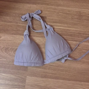 Ljuslila bikiniöverdel från H&M - Säljer en ljuslila bikiniöverdel från H&M med klassisk trekantsform och knyt både i nacken och runt ryggen. Mjuk och skön syntetmaterial som sitter snyggt och är enkel att justera. Perfekt för strandhäng och poolparty!