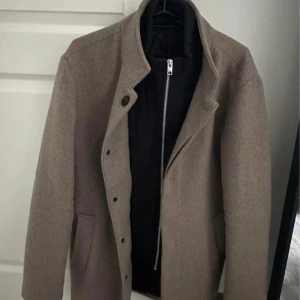 Beige ullrock  - Snygg beige rock i ull med stilren design och ståkrage. 