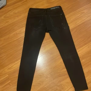 Svarta skinny jeans Alessandro Zavetti - Svarta jeans från Alessandro Zavetti i storlek 30. Modellen är skinny med slitna detaljer och små vita färgstänk på framsidan. Klassisk femficksdesign och stretchigt material för en tajt passform. Perfekt för dig som gillar en edgy och modern look.