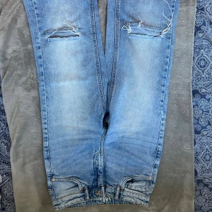 Ljusblå slitna jeans från LAB Industries - Säljer ett par ljusblå jeans från LAB Industries i storlek 158. Jeansen har slitna detaljer och hål vid knäna för en cool, avslappnad look. Klassisk femficksmodell med normal passform och tillverkade i bomullsdenim.