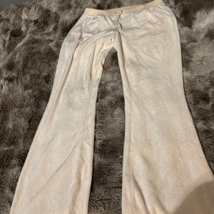 Juicy Couture set - Mysigt ljusrosa velour set från Juicy Couture med bootcut-modell och dragsko i midjan. Byxorna har fickor med lock och knapp bak samt en liten broderad logga framtill. Perfekta för en avslappnad och trendig look. Köpt för 3000, endast använd 1 gång. Tröja L byxor S