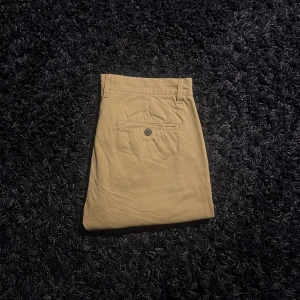 Beiga chinos slim fit från H&M L.O.G.G. - Snygga beiga chinos från H&M L.O.G.G. i slim fit-modell. Byxorna har klassisk design med bälteshällor, bakficka med knapp och är tillverkade i mjuk bomull. Perfekta för en clean och stilren look. Finns några hål som syns på bilden