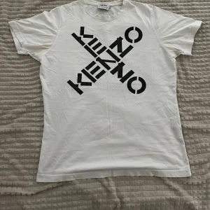 Vit Kenzo t-shirt - Säljer en vit t-shirt från Kenzo med stor svart logotyp tryckt diagonalt över framsidan. Äkta kenzo t shorts liten i storleken passar S bäst