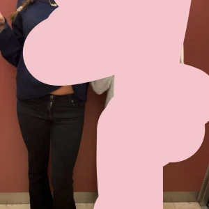 Svarta bootcut jeans  - Snygga svarta jeans med bootcut passform och klassisk femficksdesign. Byxorna har en låg midja och är perfekta för dig som gillar en tidlös stil med lite extra attityd. Passar till sneakers eller boots för en cool look.