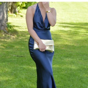 Marinblå långklänning i satin - Säljer en superfin marinblå balklänning i satin💕 Klänningen har halterneck och djup draperad urringning och även en djup öppen rygg. Perfekt för bal eller andra festliga tillfällen🩷. Supersnygg och elegant look!✨använd en gång!! (Finns lite märken på insidan av klänningen pga fashiontape men inget som syns då det är på insidan, be om bild)nypris: 1500