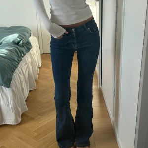 Mörkblå bootcut jeans - Snygga mörkblå jeans med bootcut passform och klassisk femficksdesign. Jeansen är tillverkade i ett stretchigt denimtyg som sitter tajt över låren och släpper ut vid bensluten. Perfekta för en trendig och avslappnad look. MÅTT: 34cm (stretchiga), 84cm