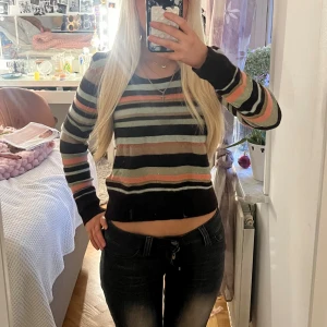Randig stickad tröja i rosa och brun - Säljer en snygg stickad tröja med randigt mönster i brunt, rosa, beige och ljusgrått. Tröjan har långärmad passform och är lite croppad i modellen. Perfekt för dig som gillar färg och vill ha en chill look.