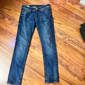 Blå skinny jeans från Jack & Jones - Snygga blå jeans från Jack & Jones med klassisk femficksdesign och smal passform. Jeansen har normal midja, tydliga kontrastsömmar och är tillverkade i stretchig denim för extra komfort. Perfekta för dig som gillar en stilren och modern look.