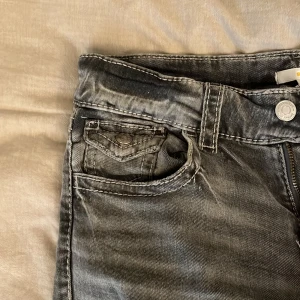 Grå bootcut jeans från Gina Tricot - Snygga grå jeans från Gina Tricot i storlek 164. Jeansen har bootcut-modell med klassiska fickor fram och bak, samt coola slitningar och detaljerade sömmar. Perfekt för dig som gillar en avslappnad men trendig look.