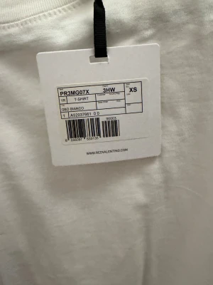 Vit ärmlös t-shirt med spets från RED Valentino - Supersnygg vit t-shirt från RED Valentino i bomull, ärmlös modell med rund hals. Nedtill finns en cool snörning och volangdetalj med svart spets som ger en unik touch. Perfekt för dig som gillar stilrena plagg med twist. Oanvänd taggar sitter kvar. Köpt i Milano