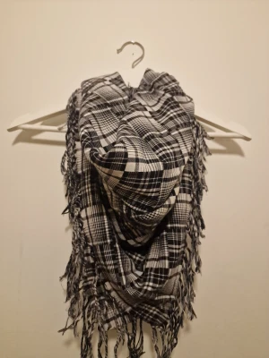 Svartvit rutig halsduk med fransar - Den är stor och mjuk, perfekt att svepa runt halsen för extra stil. Materialet känns lätt och skönt mot huden, och den passar grymt till jackor och hoodies. 100 % bomull.