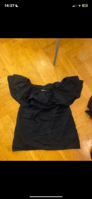 Svart offshoulder topp Gina Tricot - Säljer en svart offshoulder topp från Gina Tricot i storlek 34. Toppen har puffiga ärmar och en rak, loose passform. Materialet är mjukt och lätt, perfekt för att styla med jeans eller kjol. Enkel och stilren design som ger en cool vibe.