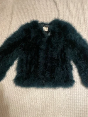 Mörkgrön pälsjacka från Pello Bello - Säljer en fluffig och stilren mörkgrön pälsjacka från Pello Bello i storlek S. Jackan har lång ärm, rund hals. Perfekt för dig som vill ha en cool och trendig look under höst och vinter.