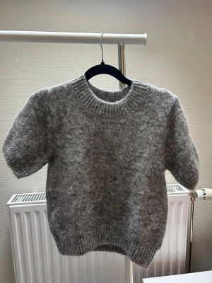 Grå stickad tröja med kort ärm - Säljer denna helt oanvända gråa stickade tröja från Gina tricot! Ordinarie pris är 299kr!