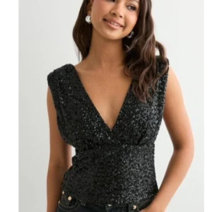 Svart paljettopp med v-ringning - Glittrig svart topp med djup v-ringning och breda axelband. Toppens yta är täckt av paljetter som ger en festlig look. Modellen är ärmlös och toppen sitter figurnära över midjan. Perfekt för att sticka ut på festen. Toppen är ny och är använd en gång! Köptes för 359kr. Skriv om de önskas flera bilder! 💓