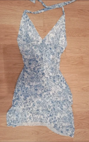 Blommig klänning - Superfin klänning med blå blommor!! Den är i mycket bra skick och endast använd ett par gånger. Banden går att knyta till både en halterneck-klänning och bandeau-klänning.🫐🌸