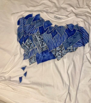 Vit t-shirt med tryck från ciconia - Superfin detaljerad vit tröja med blåa tryck. Den här tröjan är sjukt skön och snygg. #2000s #tryck #t-shirt #blått #silver #pärlad #detalier