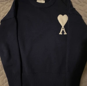 Trendig Ami de Cœuer Tröja - Perfekt Skick! - Säljer en Ami Paris tröja i mörkblått, en stilren och exklusiv design med den klassiska Ami de Cœur-logotypen broderad på bröstet.   ✔ Storlek: M ✔ Färg: Mörkblå  ✔ Skick: Helt ny ✔ Nypris: Ca 3500-4000 kr beroende på modell   En perfekt tröja för den som söker både komfort och stil. Passar utmärkt för både avslappnade vardagslook och mer dressade tillfällen.  Snabb affär = snabb leverans!