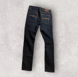 Nudie Jeans - Snygga mörkblå jeans från Nudie Jeans med klassisk femficksdesign och kontrastsömmar. Modellen har raka ben och ganska slim passform. Storlek 29/32. Jeansen är i nyskick och används fåtal gånger!😊🙌