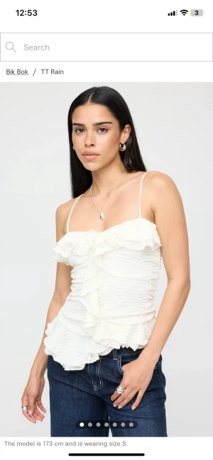 Vit omlott linnetopp med volanger Bik Bok - Supersöt vit linnetopp från Bik Bok med tunna axelband och omlottvolanger framtill. Toppen har en ribbad struktur och är figurnära med volangdetaljer längs halsringning och nederkant. Perfekt att styla med jeans eller kjol för en trendig look.