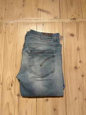 Ljusblå slitna jeans från dondup - Säljer ett par ljusblå jeans från dondup med snygga slitningar och distressed detaljer på benen. Klassisk femficksmodell. Jeansen har en cool tvättad look och är tillverkade i mjukt denimtyg.