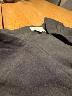 Svart klänning från Collectif - En svart, figurnära klänning från Collectif London. Klänningen har korta ärmar, cool halsringning och dragkedja i sidan för enkel påklädning. 