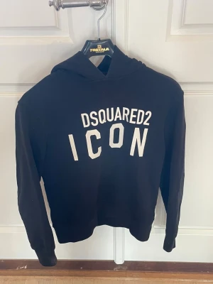 Svart hoodie DSQUARED2 ICON - Tjena! Säljer en svart hoodie från DSQUARED2 med stor vit ICON-print på bröstet. Klassisk huva och långa ärmar, ribbade muddar vid ärmslut och nederkant. Snygg streetstil som sticker ut med den feta loggan framtill. Storlek: xs. Skic:k 8/10. 
