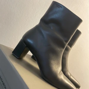 Svarta stövletter från Vagabond - Snygga svarta stövletter från Vagabond med spetsig tå och låg klack. Skorna är tillverkade i slätt skinn och har dragkedja på sidan för enkel på- och avtagning. Perfekt till höstens och vinterns outfits för en stilren look.