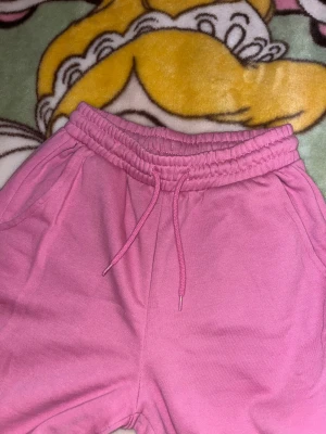 Rosa mjukisbyxor med snörning - Säljer ett par chill rosa mjukisbyxor med bred resår i midjan och snörning framtill. Byxorna har raka ben och sidofickor, perfekta för att hänga hemma eller dra till gymmet. Mjukt material som känns skönt mot huden.